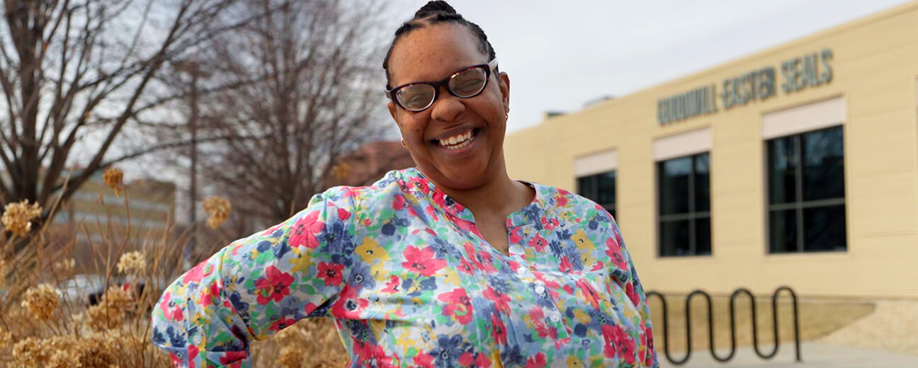 Tatiana stands with hand on hip, smiling in front of Goodwill-Easter Seals Minnesota building in St. Paul, Minnesota
