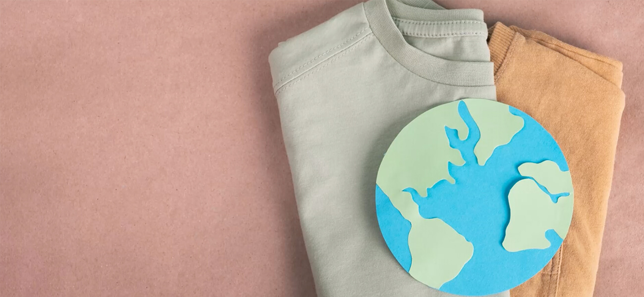 Two folded t-shirts with a paper cut out of the Earth