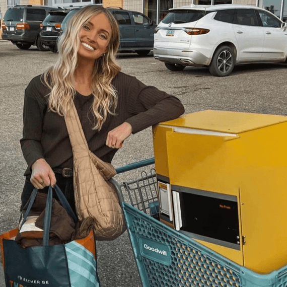 A female holding a "I'd rather be thrifting" Goodwill tote bag