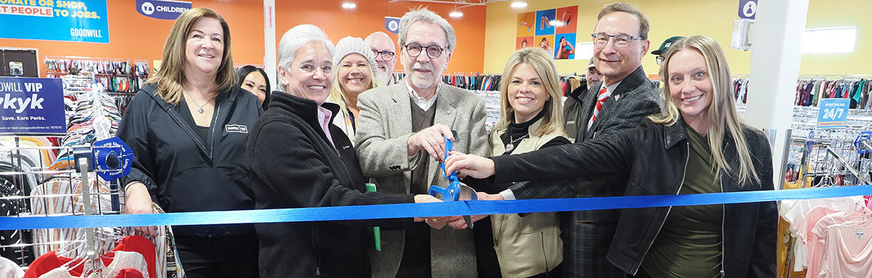 Photo of ribbon cutting with blue ribbon and large scissors at Waconia store