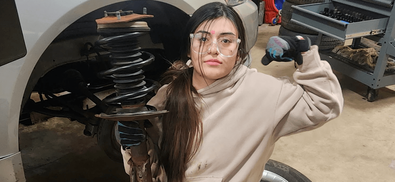 Person wearing a hoodie and safety glasses, holding a power tool.